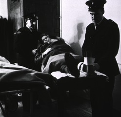 Middlesex Hospital, London, England: Patient lifted onto couch in casualty receiving room by ambulance men
