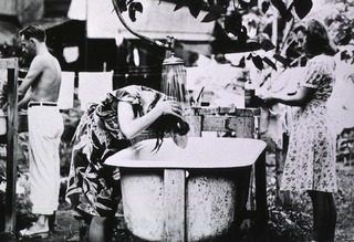 Santo Tomas Prison Hospital, Manila, P.I: Woman washing her hair at one of the two bath tubs in camp