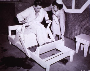 Gymnastics - Medical: Patient, with the aid of a nurse uses a rowing machine