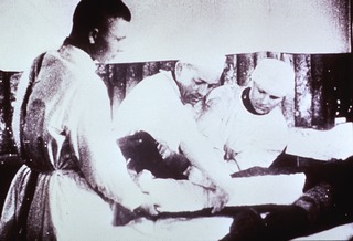 Military: Field Medical Services: View showing Soviet medics in field dispensary placing splint on leg of patient