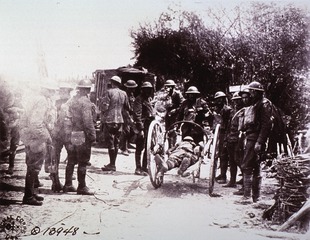 Stretchers: Wounded man being carried away on rolling stretcher from Regimental Aid Station, near Cantigny, France