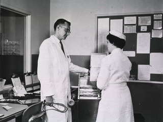 [A physician and a nurse discuss a patient's chart at the nursing unit in the Clinical Center]
