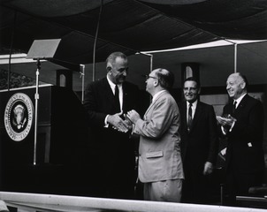 [President Lyndon Johnson greets Wilbur Cohen at the ceremony for the signing of the Health Research Facilities Act]