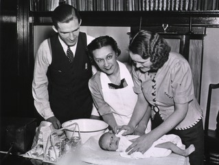 [Nurse instructing parents on how to bathe their baby]