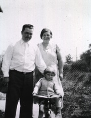 [Child on a tricycle with his parents]