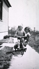 [Child on a tricycle with Miss Kramer]