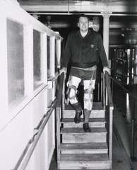 [A man with two prosthetic legs exercising on a set of steps in a rehabilitation center]