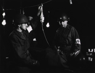 A casualty being treated by a doctor and two aidmen in a division surgery tent, December 14, 1951