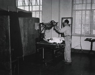 A technician prepares to X-ray a patient at the 5th Field Hospital, Santo Tomas University, Manila, Luzon, P.I