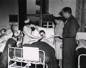 [Army Nurse 2nd Lt. Lucille V. Healy administers oxygen to a patient]
