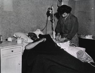 [Army Nurse 2nd Lt. Beatrice Manley prepares intravenous injection for patient]