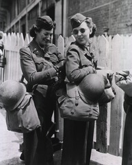 [Army Nurses adjust their equipment while they wait to board transport]