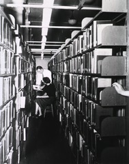 [Miss Harvin and Mr. Weaver confer in the stacks]