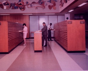 [Reference librarian Howard Drew stands in between card catalogs in the library rotunda]