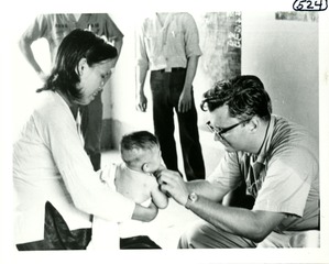 [Dr. Mackler examines a Vietnamese infant held by its mother]