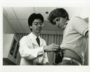 [A physician instructs a patient in the use of an insulin pump]