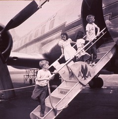 [Four children (full length portrait) climbing up and down the stairs of an airplane]