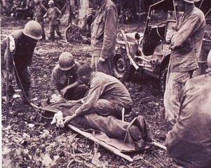 [A wounded infantryman is treated at a first aid station]