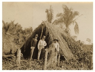 Fred L. Soper, Wilbur A. Sawyer, and their guide in front of a shelter at the site of a yellow fever infection near Coronel Ponce, Mato Grosso, Brazil