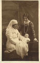 [Nurse holding a baby with woman behind them]