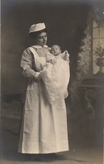 [Nurse standing and holding a baby]