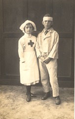 [Girl dressed as a nurse standing next to a boy with a bandaged head]