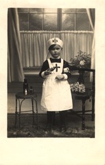 [Child dressed as a nurse holding a medicine bottle]