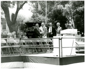[Dignitaries stand near the speaker's podium during the National Library of Medicine groundbreaking ceremony]