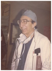 Michael DeBakey, in lab coat and surgical cap, smiling