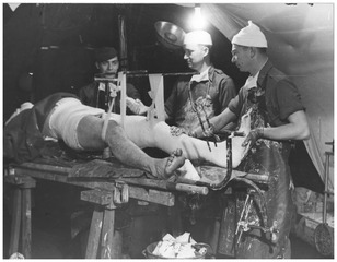 Captain Clarence Brott applying a cast to the leg of a soldier with a deep wound in his thigh by a shell fragment, 94th Evacuation Hospital, 2nd Auxiliary Surgical Group