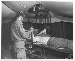 Corporal Alejandro Aquino, x-ray technician, 8076th Mobile Army Surgical Hospital, taking an x-ray of a soldier's arm for possible fracture